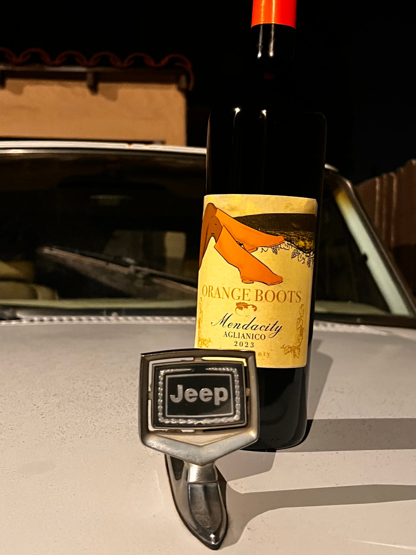 Bottle of Orange Boots wine with a Jeep logo on a car's rearview mirror