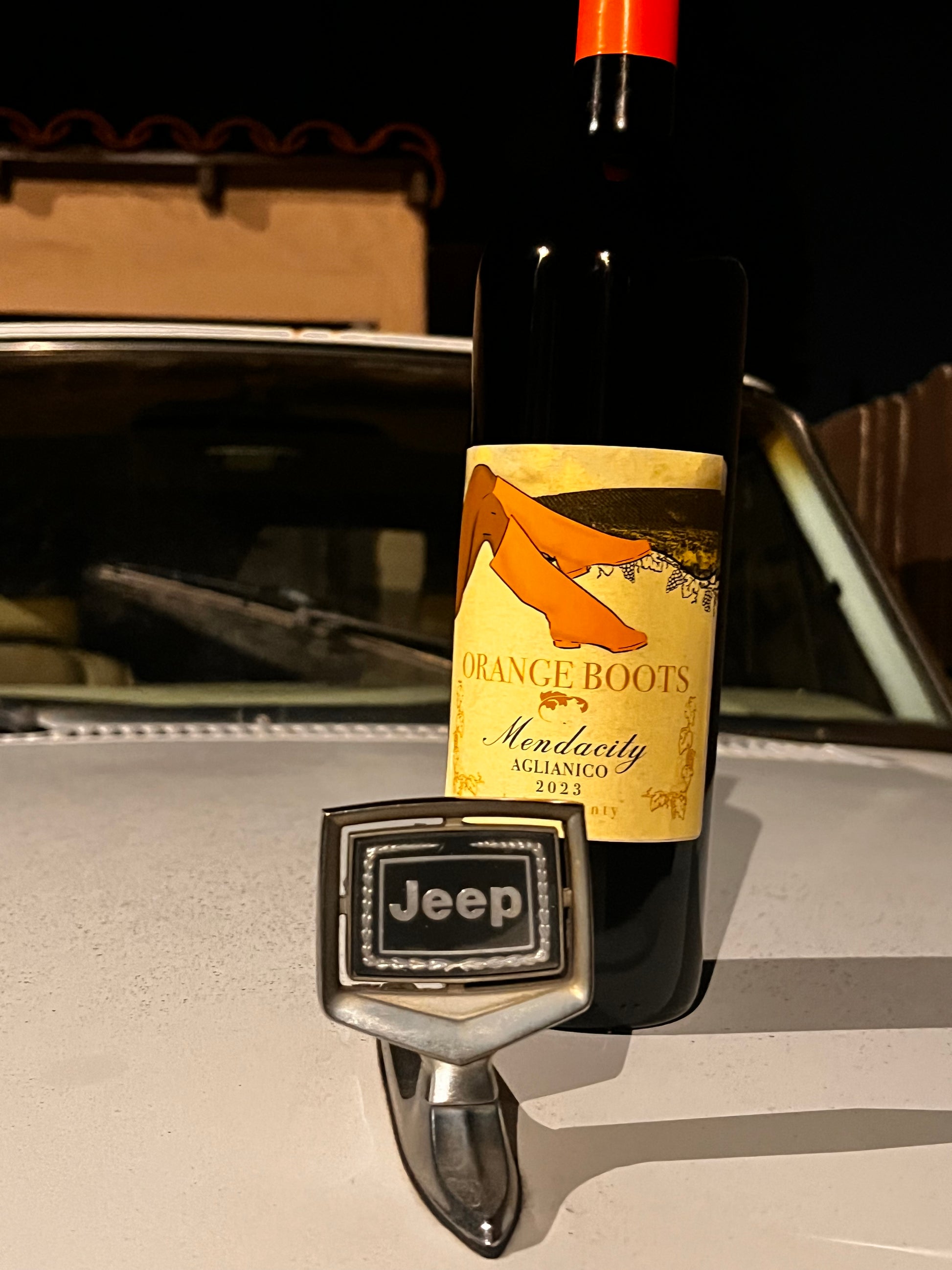 Bottle of Orange Boots wine with a Jeep logo on a car's rearview mirror